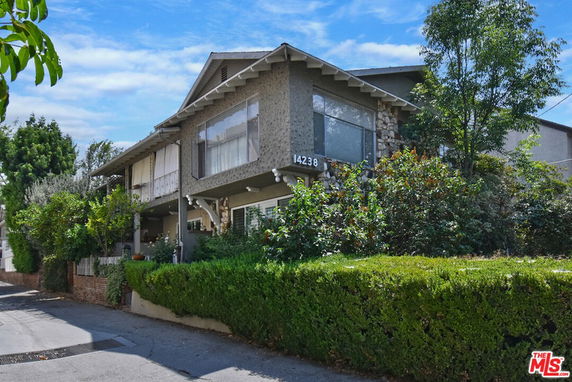 Front view of a two-story house with a prominent balcony and lawn.