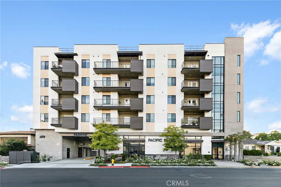 Front view of a multi-story apartment building with balconies and parking signage.
