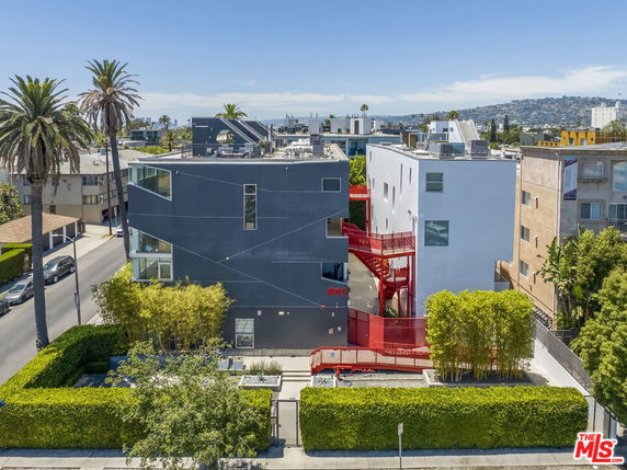 Front view of a modern multi-story building with a unique design and vibrant red accents.