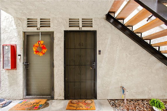 Entrance area of a building with two doors numbered 61 and 63 under a staircase.