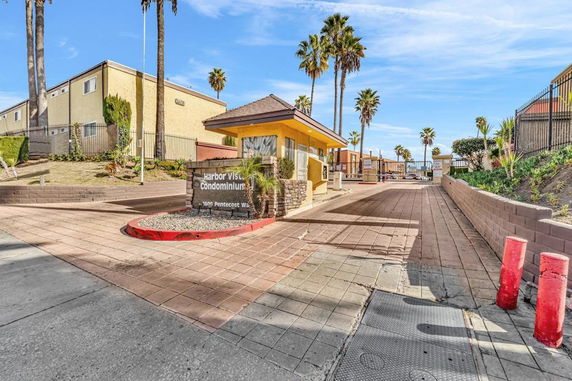 Front view of condominium entrance with a security building and gated access.