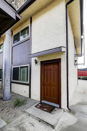Front view of a two-story house with a brown door and textured walls.