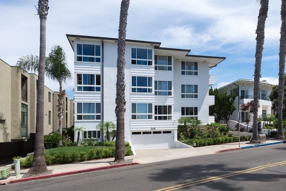 Front view of a multi-story building with large windows and a white facade.
