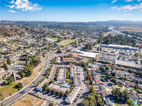 Aerial view of a residential area with an apartment complex surrounded by roads, shopping centers, and greenery.