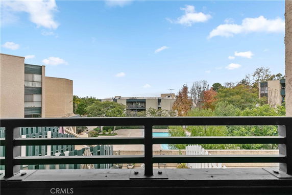 View from a balcony overlooking residential buildings and a pool.