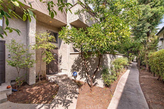 Front view of a multi-story residential building with a walkway and plants.