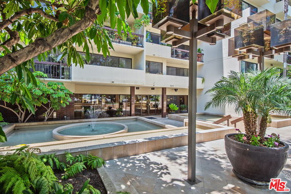 Front view of a multi-story building with balconies and a central water fountain