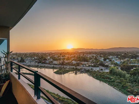 Sunset view from a balcony overlooking a cityscape and waterway.