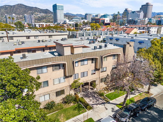 Rooftop view of a three-story residential building with visible air conditioning units and adjacent buildings.