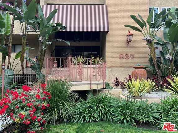 Front view of a building entry with a striped awning and brick facade.