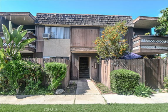 Front view of a two-story house with wooden exterior and balconies.