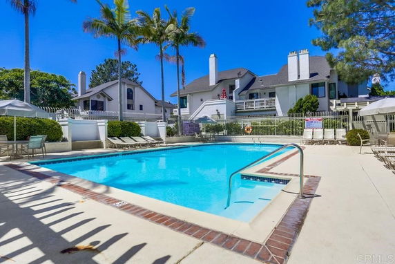 Outdoor swimming pool area with surrounding houses.