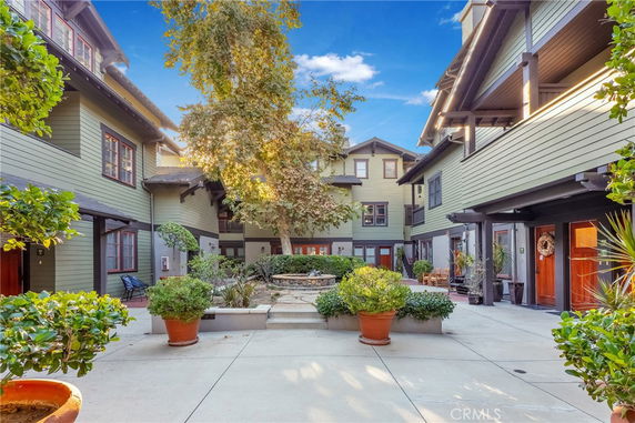 Courtyard view of a multi-story residential building with green exterior and plants.