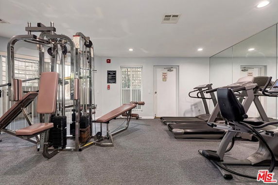Indoor gym area with fitness equipment including treadmills and weight stations.