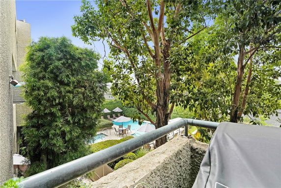 View from a building overlooking a swimming pool area with trees and umbrellas.