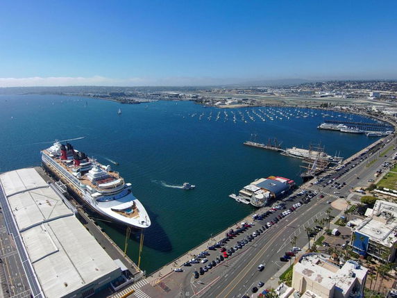 Panoramic view of a harbor with a cruise ship docked and surrounding cityscape.