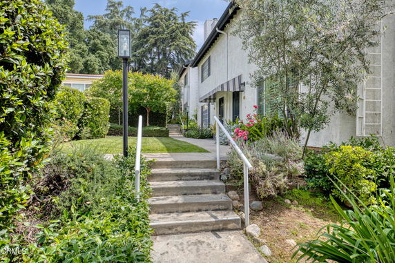 Front view of a two-story house with a pathway and surrounding greenery.