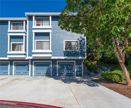 Front view of a multi-story building with blue siding and multiple garage doors.