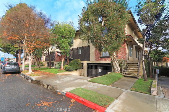 Front view of a two-story house with stairs leading to the entrance and a garage underneath.
