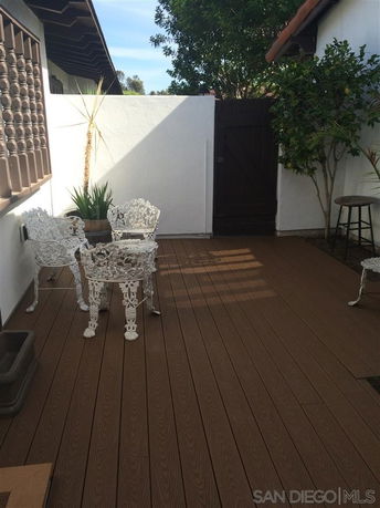 Outdoor patio area with decorative chairs and plants against white walls.