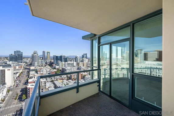 Wide balcony with glass railing offering a panoramic view of the cityscape.