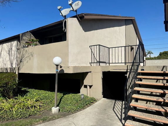 Front view of a building with external staircase and satellite dishes on the roof.