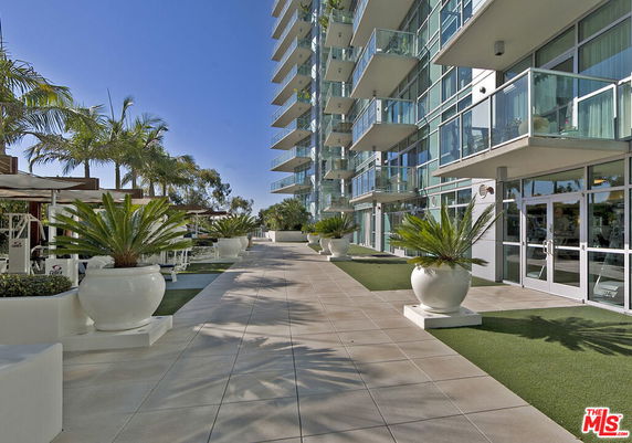 View of a modern multi-story building with glass balconies and planters.