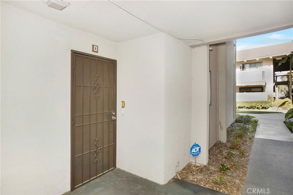 Exterior view of a building entrance with a metal door marked 'D'.