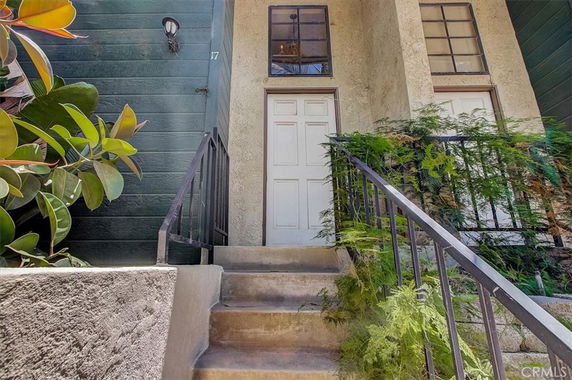 Front view of a building entrance with stairs and a white door.