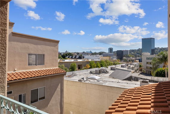 Panoramic view showing rooftops and distant buildings under a blue sky.