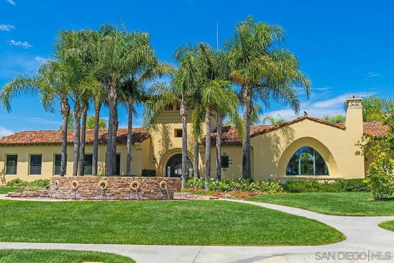 Front view of a house with arched windows and palm trees.