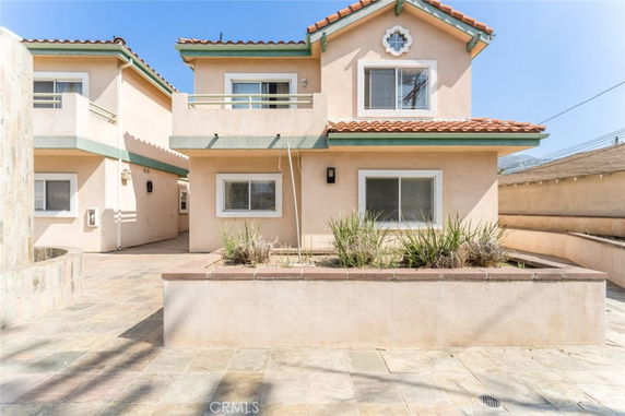 Front view of a two-story house with a balcony and tiled roof.