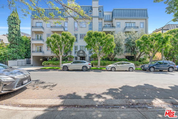 Front view of a multi-story residential building with balconies and a covered entrance.