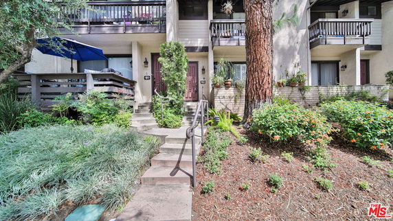 Front view of a multi-story residential building with balconies and landscaped entrance.