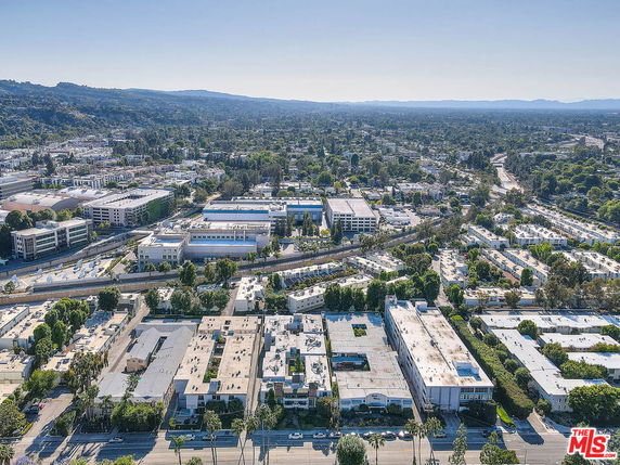 Aerial panoramic view of a city with multiple buildings and greenery in the background.