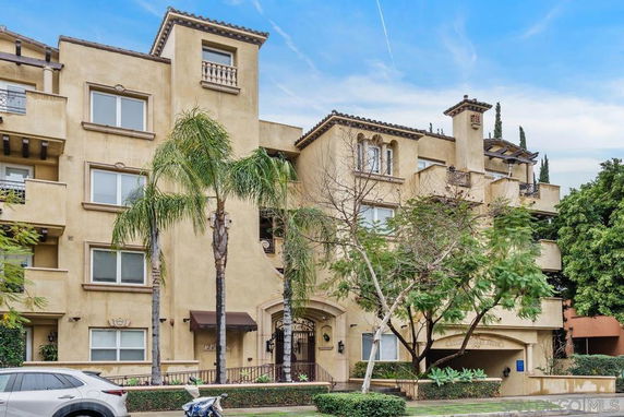 Front view of a multi-story residential building with balconies and arched entrance.