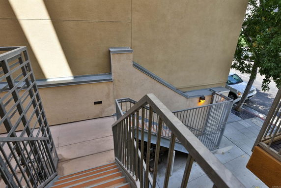 Exterior view of a building with stairway leading down, adjacent to a sidewalk and street.