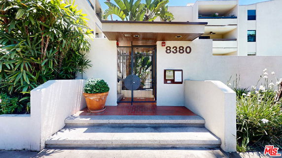 Front view of a building entrance with a gated entryway and steps leading up.