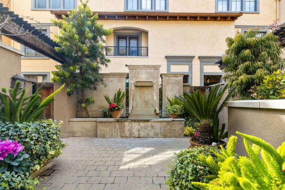 Front view of a multi-story building with a small garden and water feature in the courtyard.