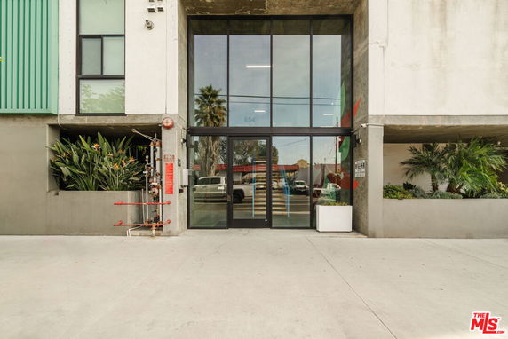 Front view of a building entrance with glass doors and surrounding greenery.