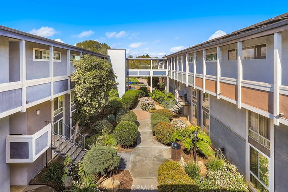 View of a two-story apartment building with walkways and garden landscaping.