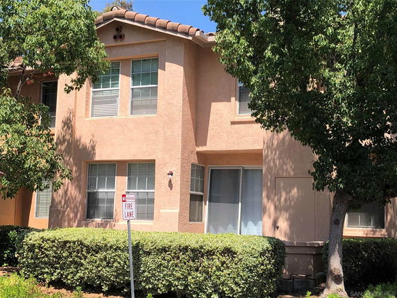 Front view of a two-story house with beige stucco exterior and multiple windows.
