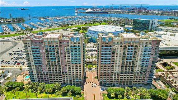 Aerial view of two tall residential buildings with nearby marina and waterfront.