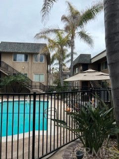 Outdoor swimming pool area with adjacent residential buildings and palm trees.