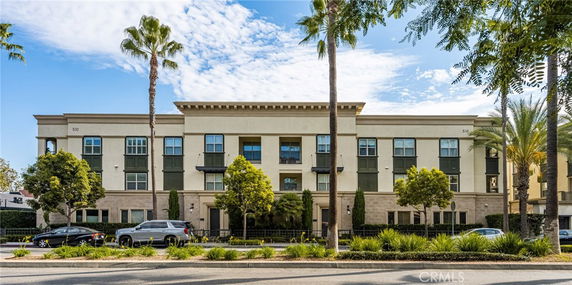 Front view of a multi-story apartment building with columns and balconies.