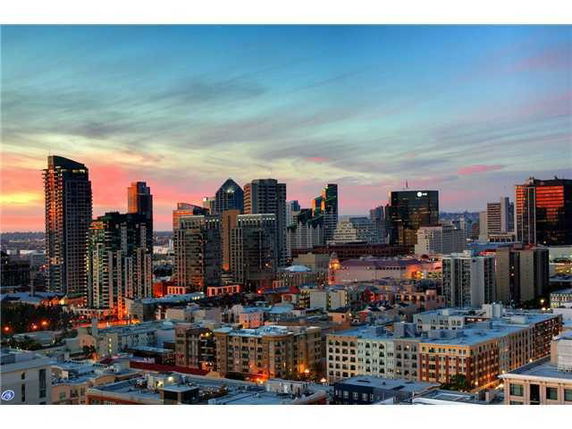 Panoramic view of a cityscape at sunset with multiple skyscrapers and buildings.