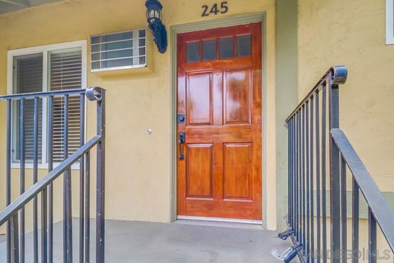 Front view of a house with a wooden door and metal railings.