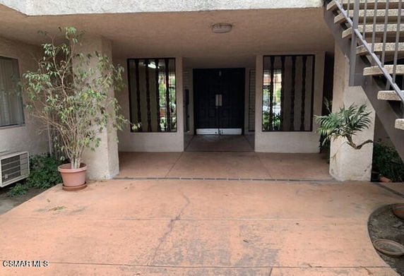 Front view of a building entrance with stairs on the side.