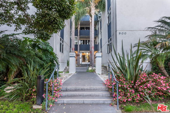 Front view of a multi-story residential building with a pathway leading to the entrance.