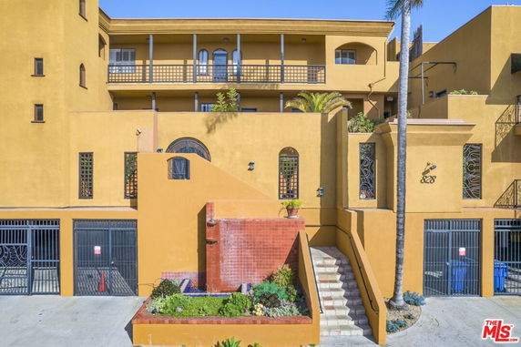 Front view of a multi-story building with a staircase and gated entrances.
